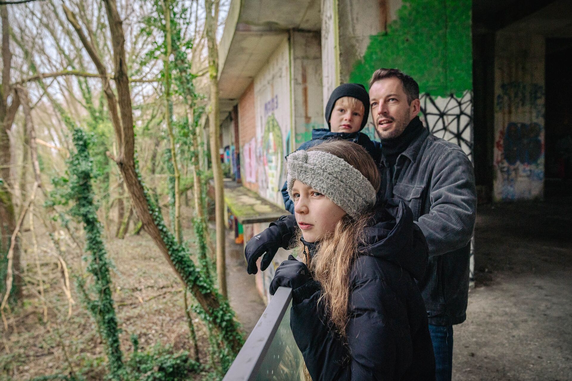 Besuchen Sie die Hotelruine im Vrijbroek-Park in Mechelen. Ein Mann und zwei Kinder schauen sich bei ihrem Besuch der Hotelruine im Vrijbroek-Park in Mechelen neugierig um.