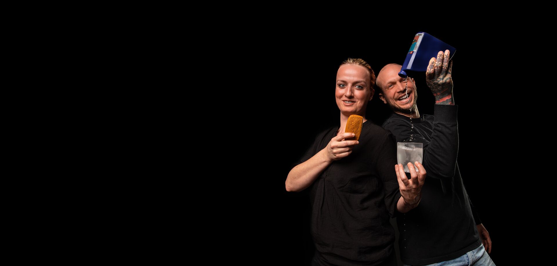 Een vrouw heeft een koekje vast terwijl een man haar glas vult.