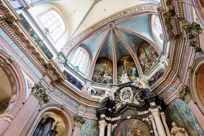 Ornate cathedral interior with a vibrant frescoed dome, intricate arches, and detailed sculptures. The atmosphere is grand and awe-inspiring.