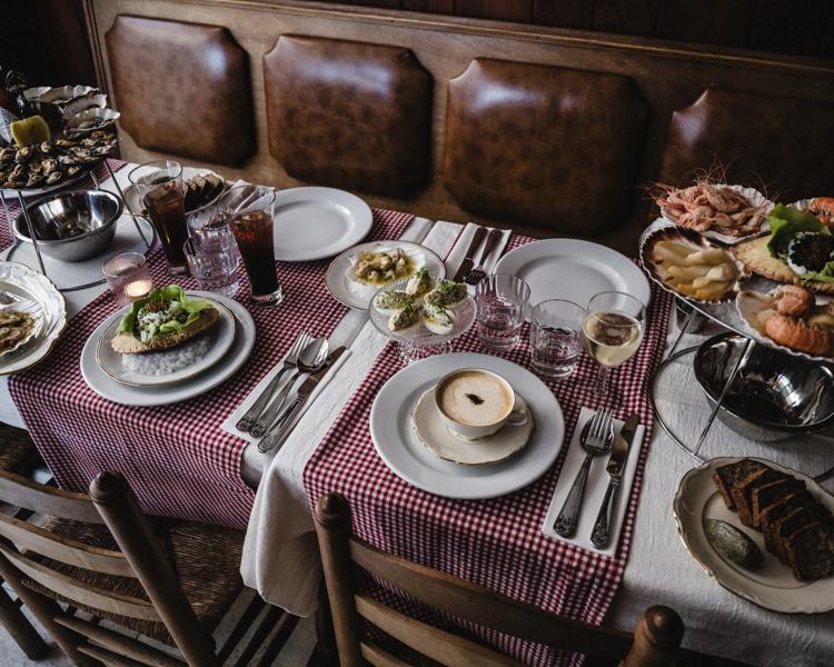 Set table with red-and-white checkered cloth, plates, cutlery, drinks, and a seafood platter in a restaurant.