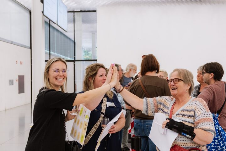 2 personen geven elkaar glimlachend een high-five tijden het Rap op Stap-congres van het initiatief Iedereen Verdient Vakantie.