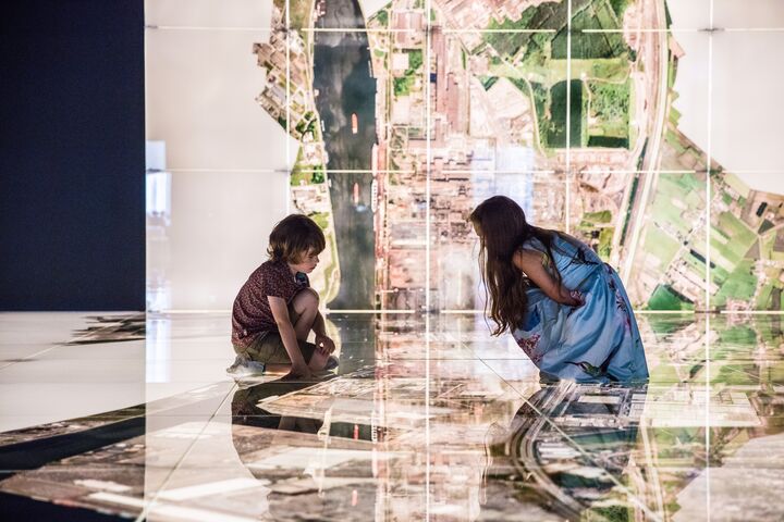 2 kinderen bewonderen een projectie van de stad Ghent op de vloer.