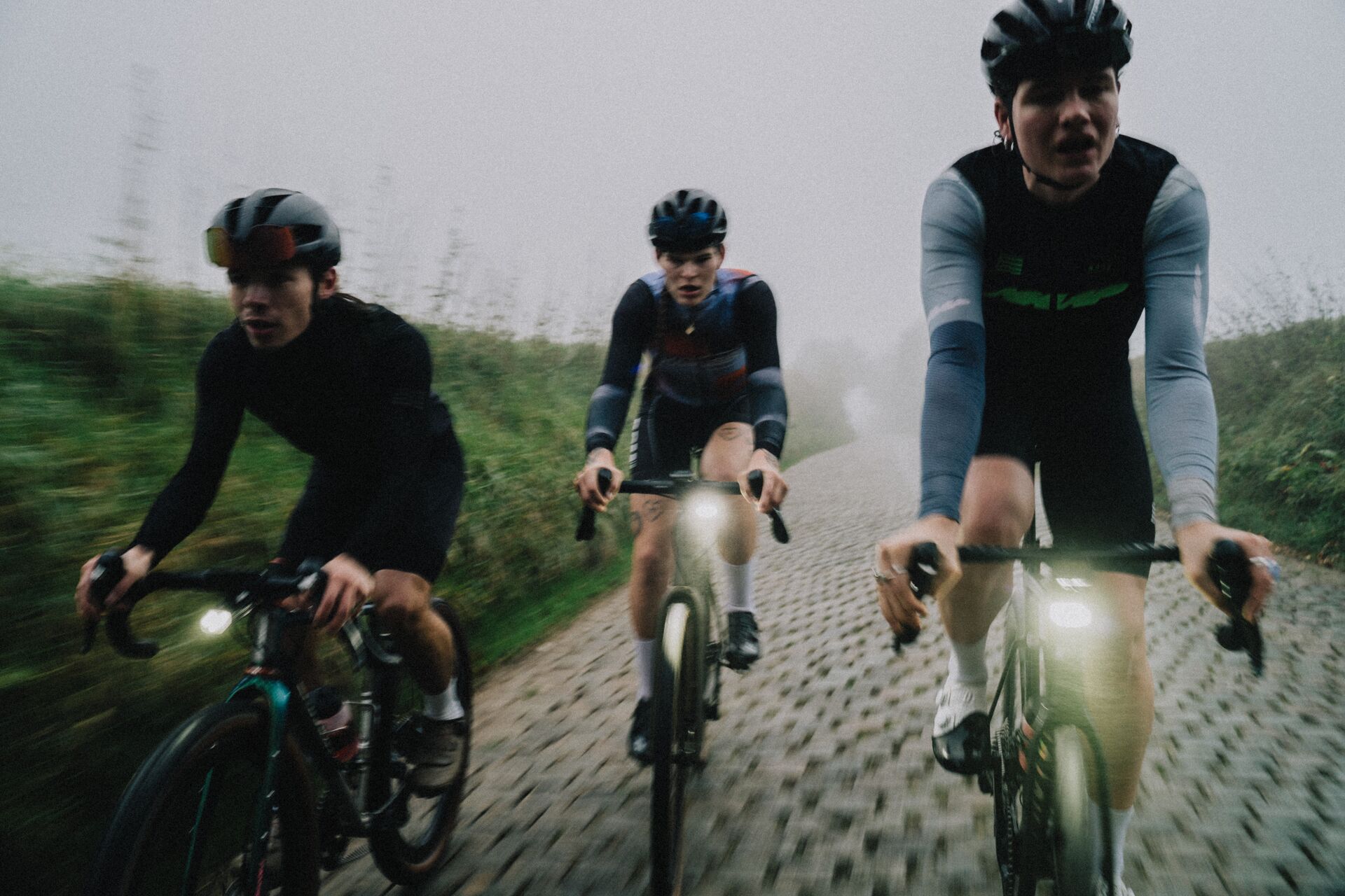 3 cyclists riding on the cobbles in Flanders at sunrise