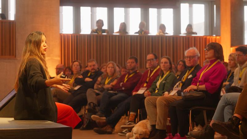 Een vrouw geeft een lezing over toegankelijke en inclusieve events voor een publiek op het congres van Meet in Flanders Academy.