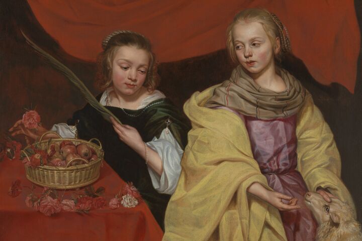 Twee jonge meisjes in elegante kleding zitten tegen een rood gedrapeerde achtergrond. De ene houdt een palmtak en een fruitmand vast; de andere raakt zachtjes de kop van een lam aan.