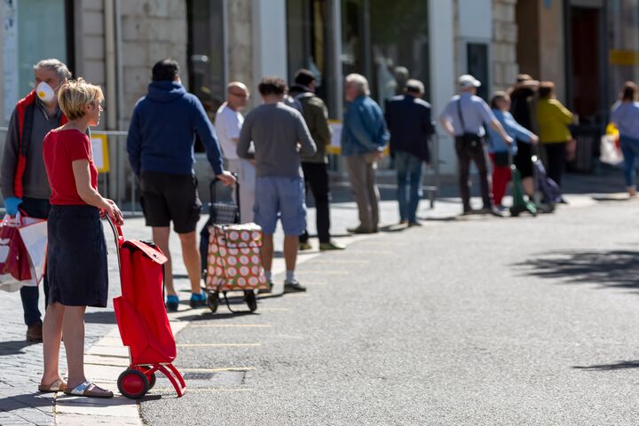 Er staat een lange rij mensen te wachten voor een winkel.