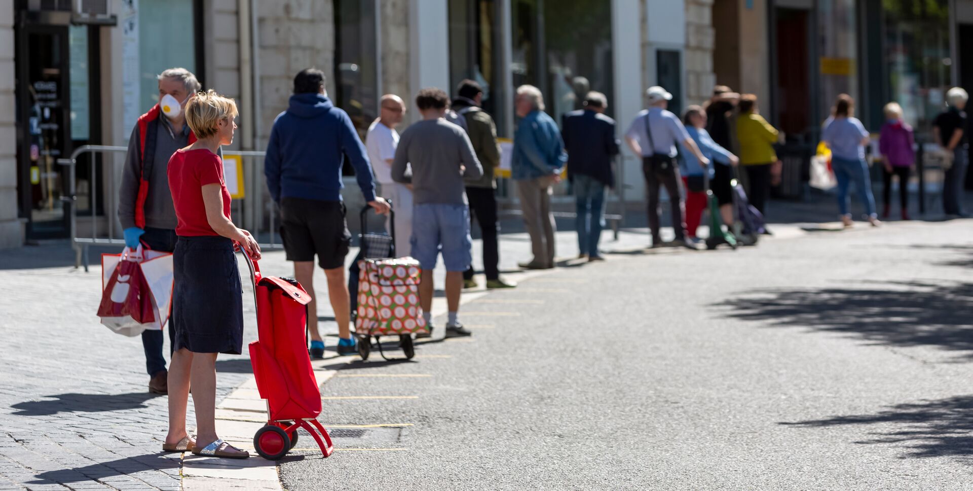 Er staat een lange rij mensen te wachten voor een winkel.