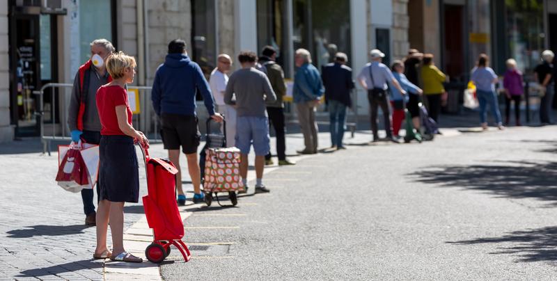 Er staat een lange rij mensen te wachten voor een winkel.