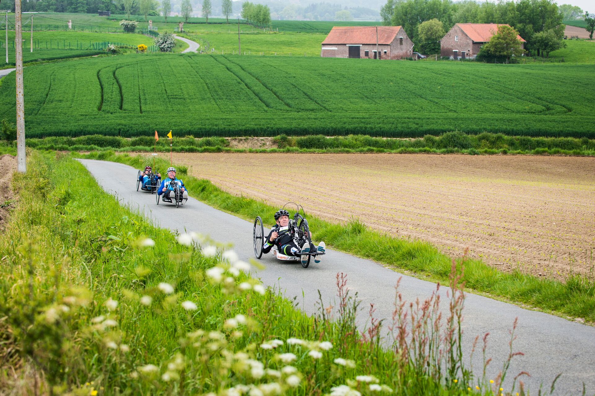 Handbikers cycling in a rural landscape in Flanders