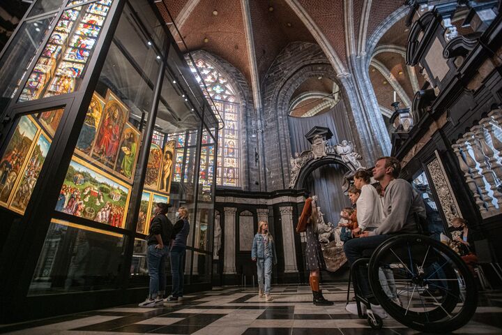 Hombre en silla de ruedas admirando el Cordero Místico en la catedral de San Bavón en Gante