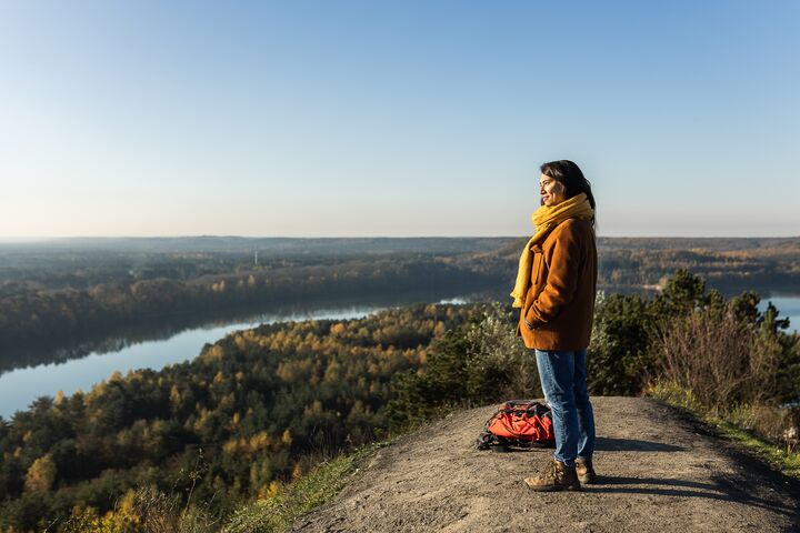 Une femme admire la vue depuis une colline le long d&#039;une rivière dans le Parc National de la Haute Campine.
