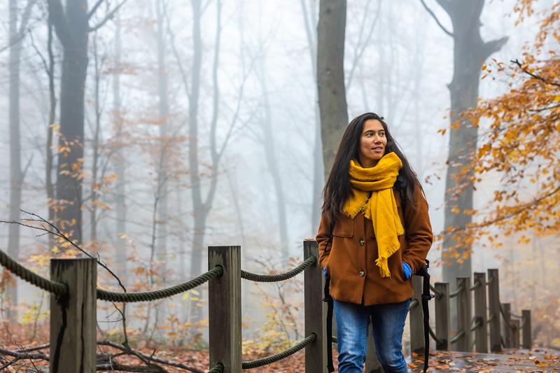 Een vrouw bezoekt de vallende bladeren van het Kluifbos in de herfst.